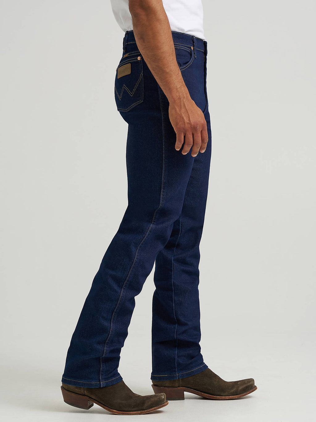 Side view of Wrangler 13MAFPW Active Flex jeans in Prewashed Indigo worn with boots.