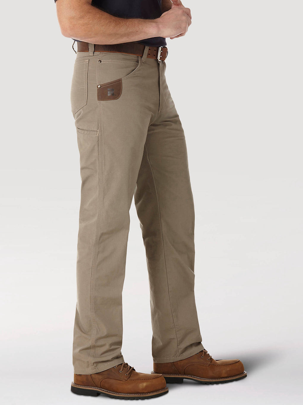 Side view of Wrangler 3W045DK RIGGS Technician pants in Dark Khaki worn with work boots.