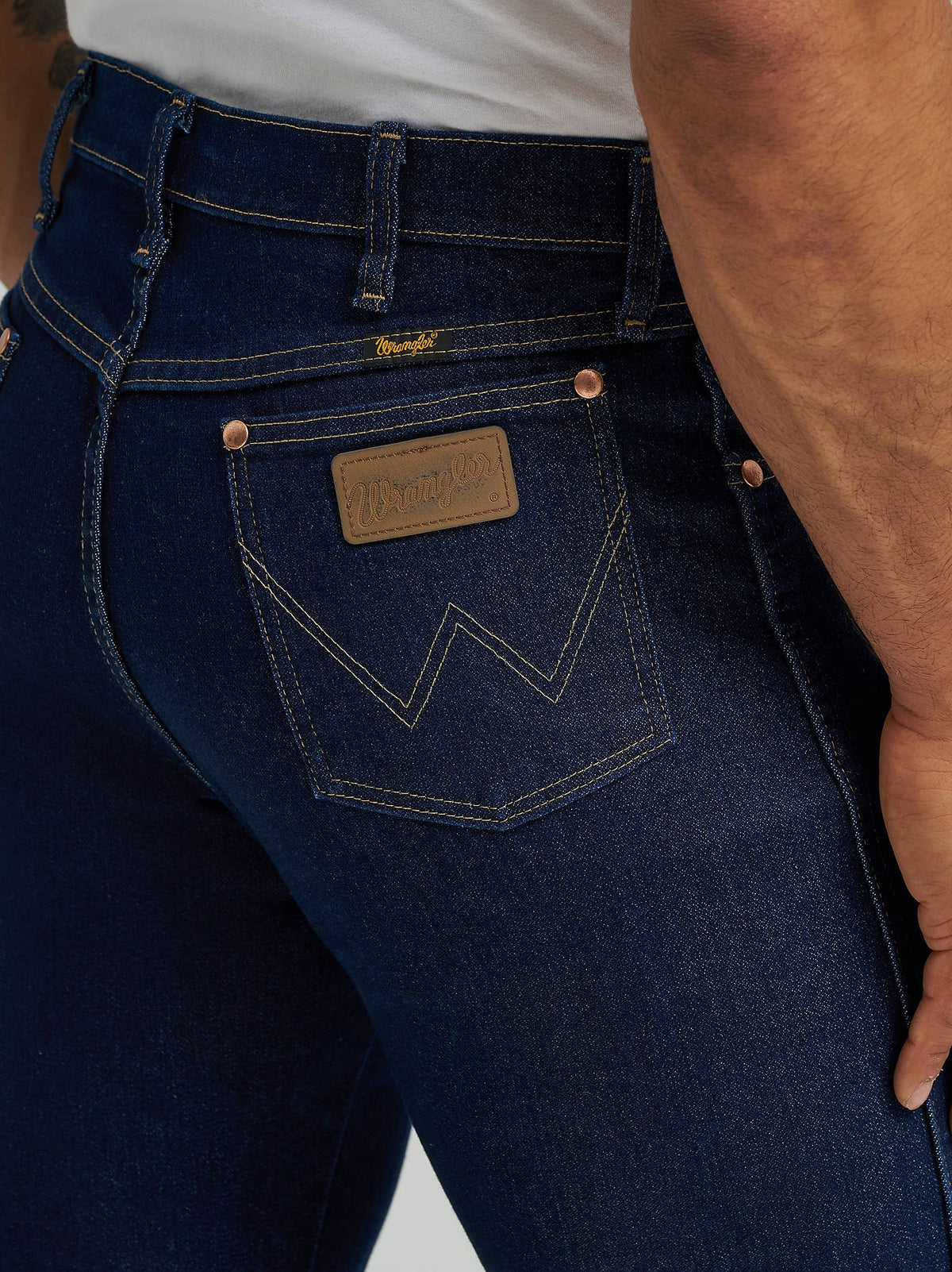 Close-up of the Wrangler patch and W stitching on the rear pocket of Prewashed Indigo Active Flex jeans.