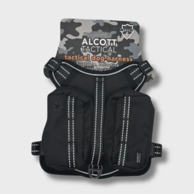 A black tactical dog harness with two storage pouches and reflective trim on a display card.