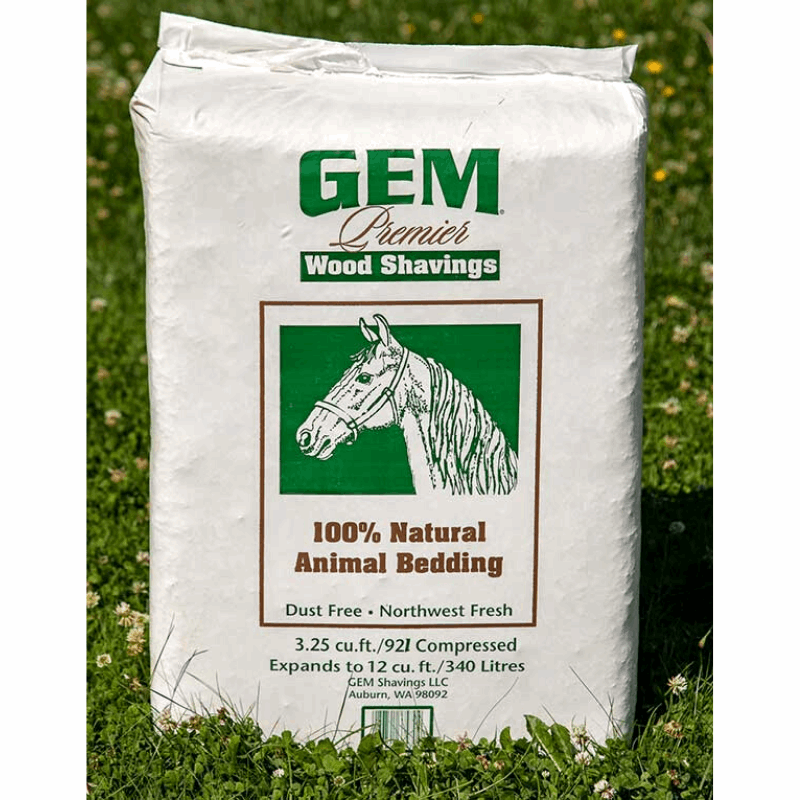 A bag of GEM Premier wood shavings for animal bedding sitting on a grassy lawn.