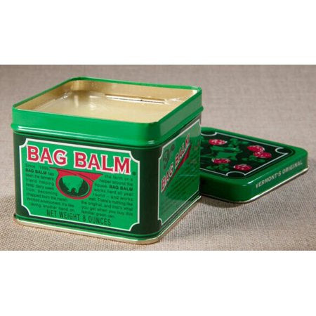 An open green tin of Dairy Association Bag Balm with its lid resting beside it.