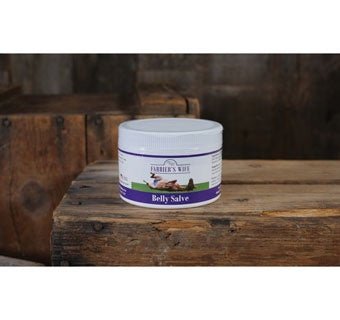 A white jar of Animal Health Belly Salve sits on a rustic wooden surface.