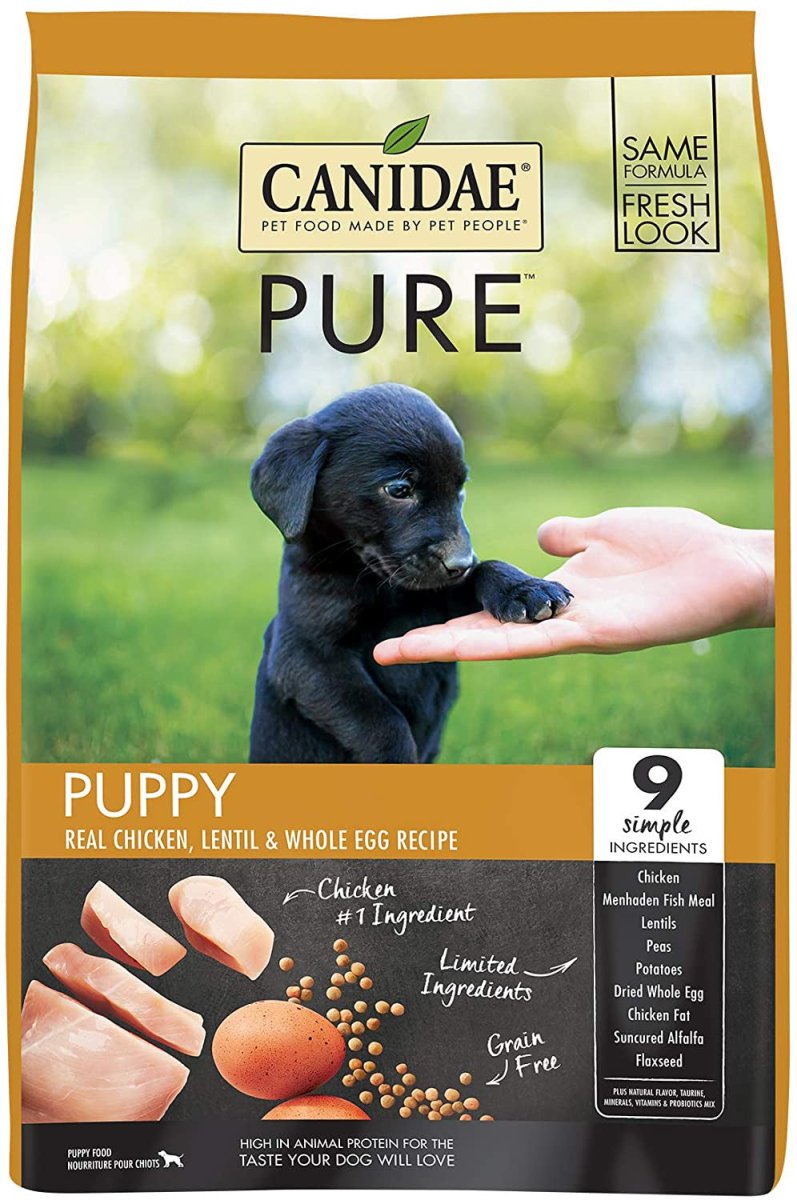 A bag of Canidae Pure puppy food featuring a black puppy and images of chicken, lentils, and eggs.