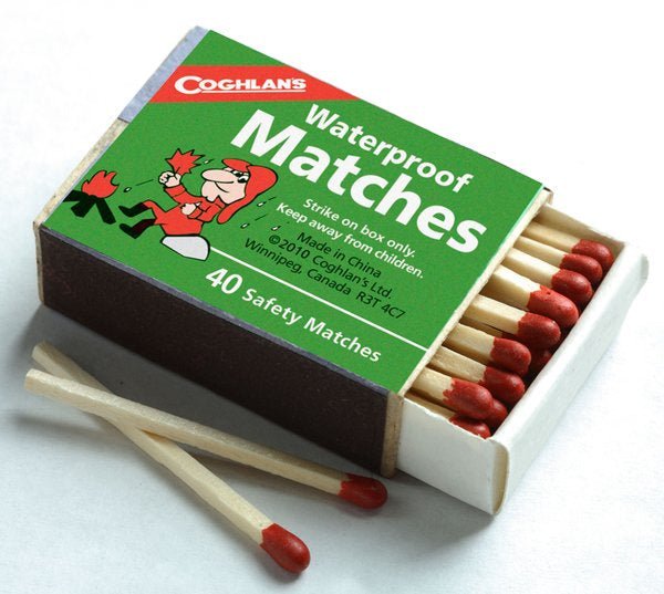 A box of Coghlan's waterproof matches with two loose matches resting in front.
