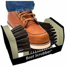 A brown leather boot rests inside a black and tan Jobsite boot scrubber with stiff bristles.