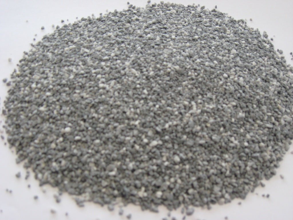 A pile of grey and white limestone feed flour granules on a white background.