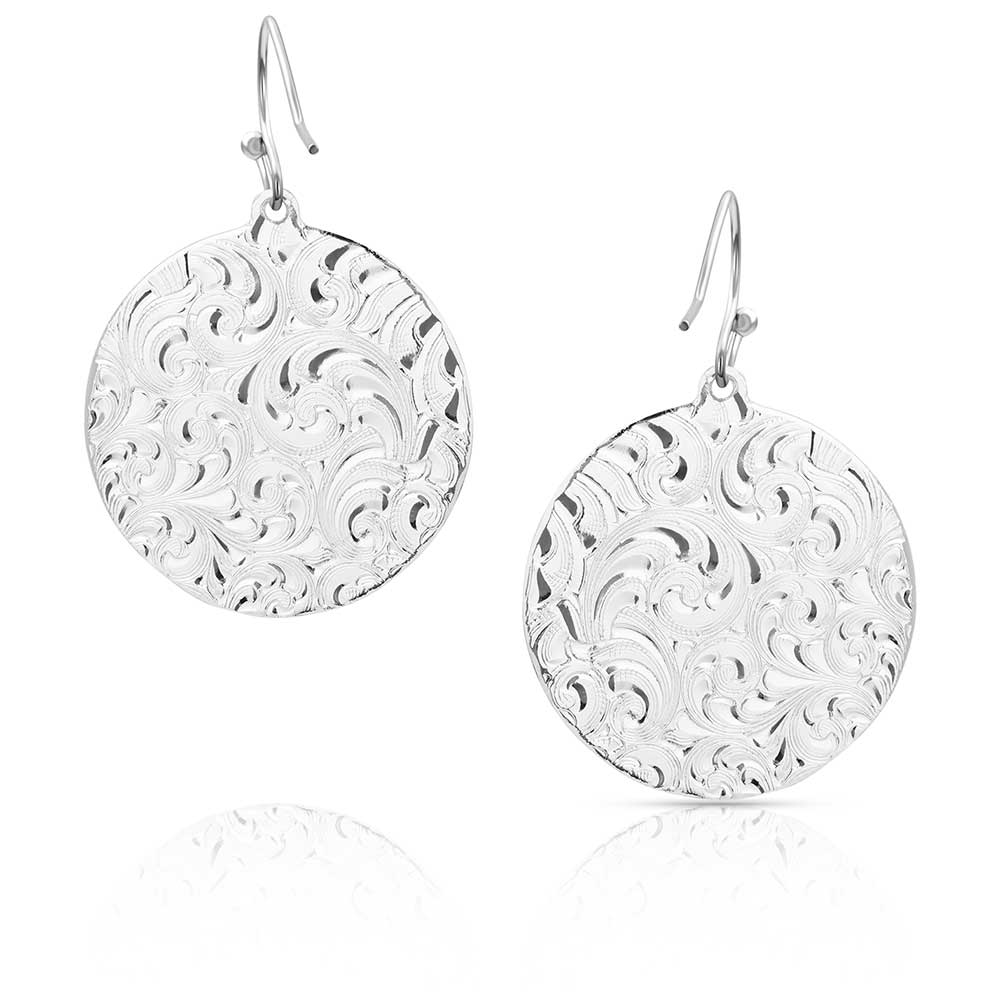 A pair of silver-toned circular drop earrings featuring an intricate engraved scrollwork pattern.