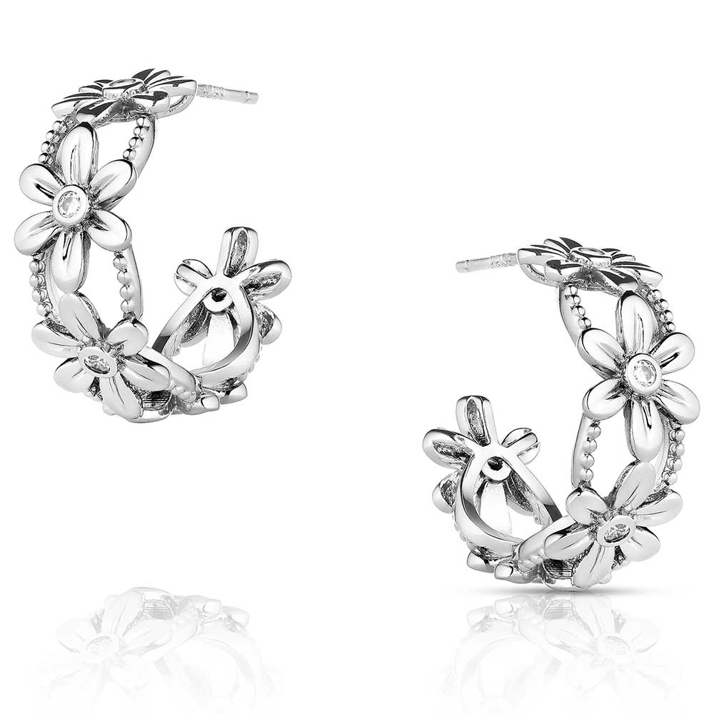 A pair of silver-tone hoop earrings featuring a floral design with cubic zirconia centers.