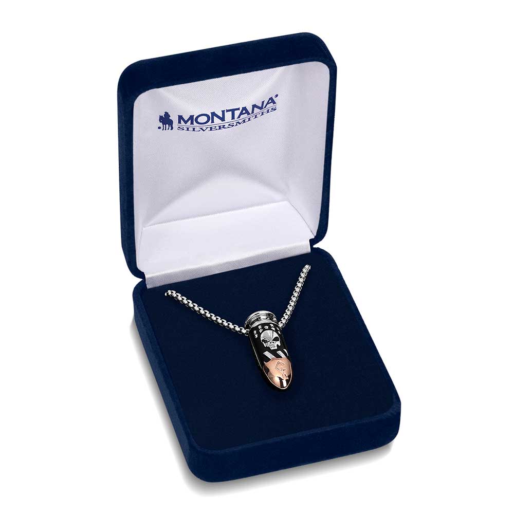 A bullet-shaped pendant with a skull design on a silver chain inside a blue velvet box.