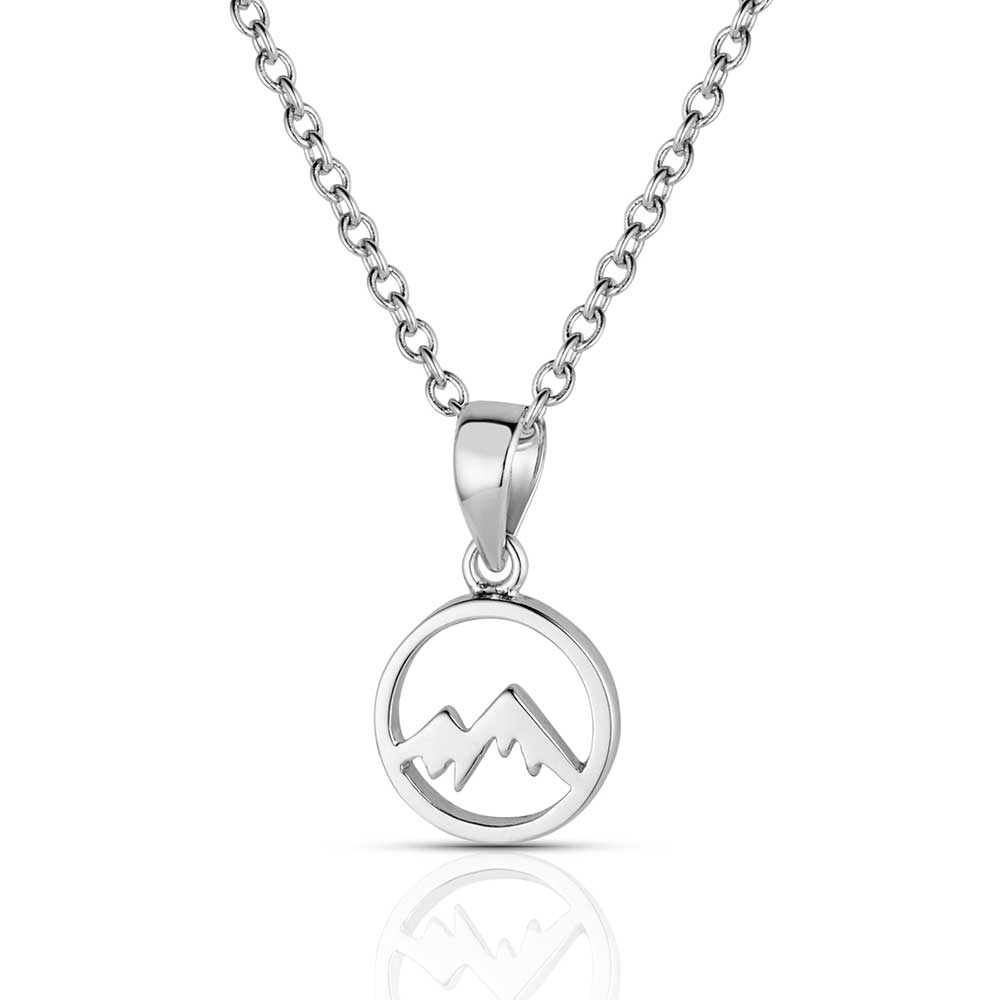 A silver tone necklace featuring a circular pendant with a mountain peak cutout on a chain.