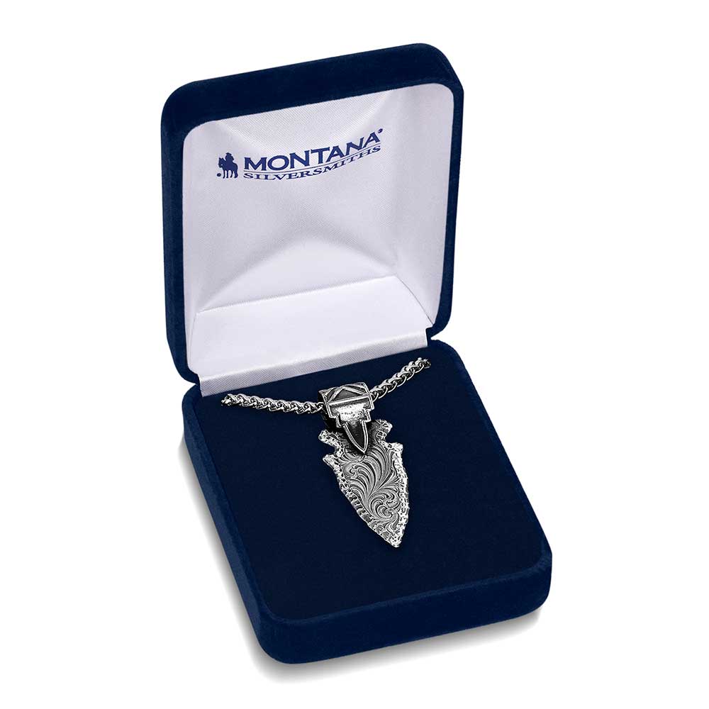 A gunmetal arrowhead pendant with Western engraving on a silver tone wheat chain in a gift box.