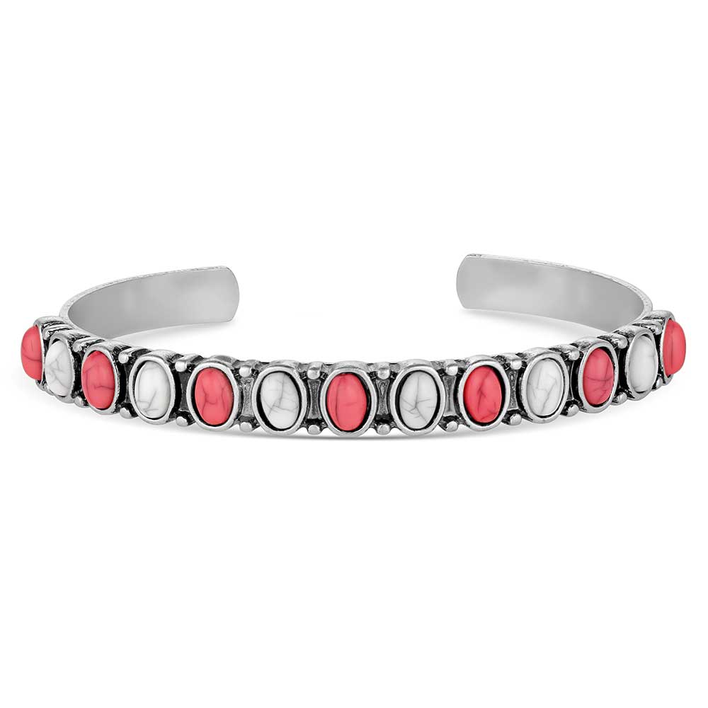 A silver tone cuff bracelet featuring alternating oval red and white stones with western detailing.