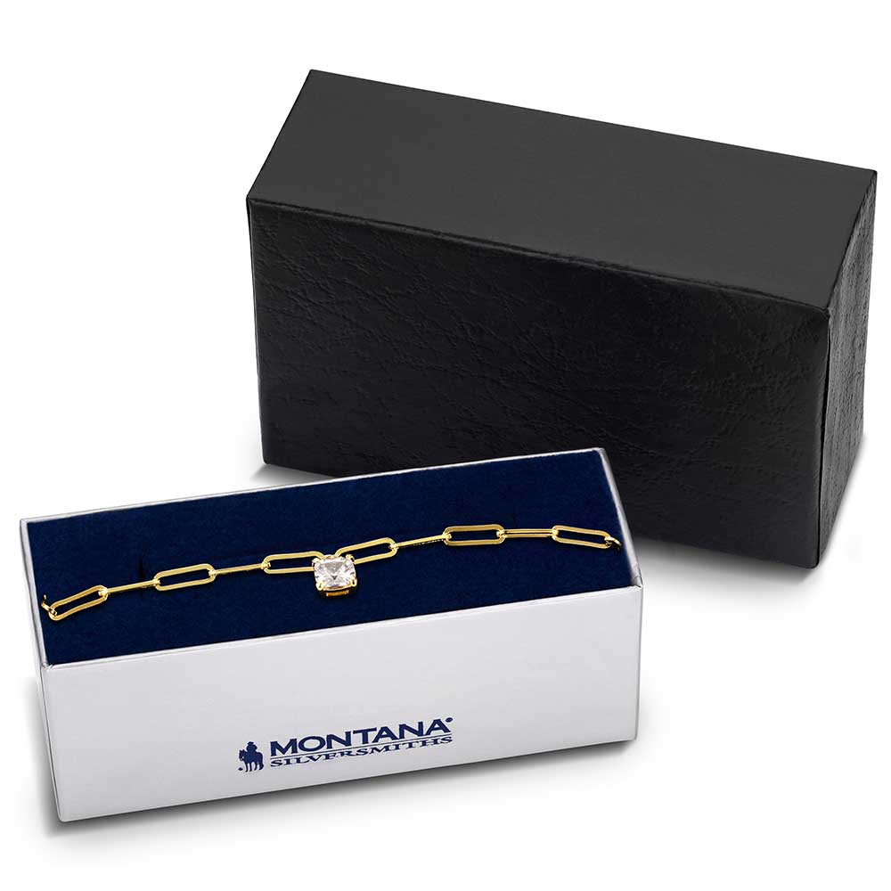 A gold chain bracelet with a central solitaire stone displayed in a Montana Silversmiths box.