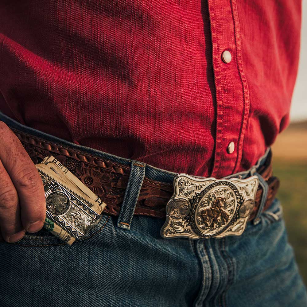 A silver money clip featuring an engraved buffalo nickel design held in a person's pocket.
