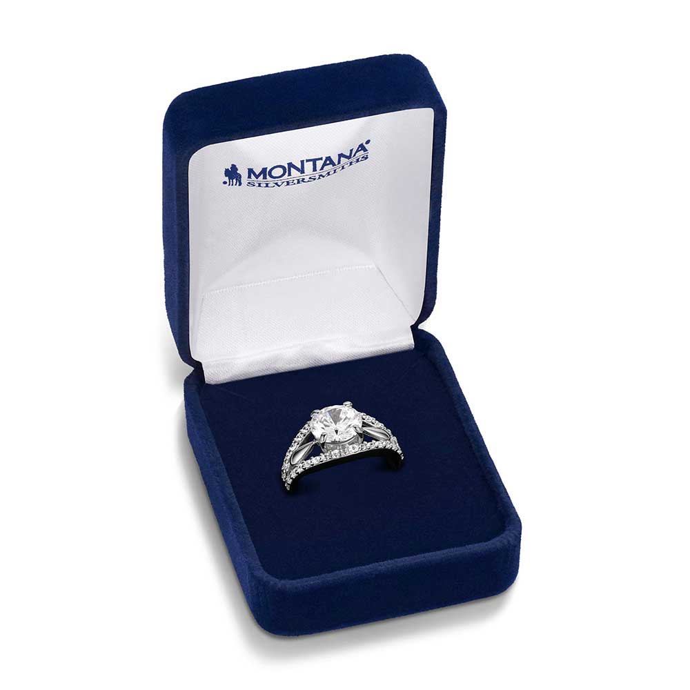 A Montana Silversmiths ring with a large center stone and pavé bands inside a blue velvet box.