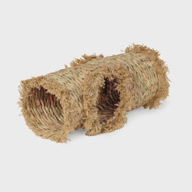 A woven grass tunnel for small pets with a side opening and frayed edges.