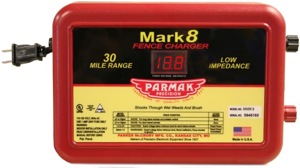 A red Parmak Mark 8 electric fence charger with a digital voltage display and power cord.
