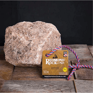 A large, natural mineral salt rock hangs from a red, white, and blue rope with a product tag.