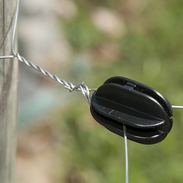 A black plastic corner post insulator attached to a wire fence post.